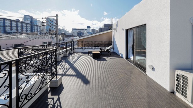 Una terrazza sul tetto con ringhiera in metallo, una panca in cemento e vista sulla città.