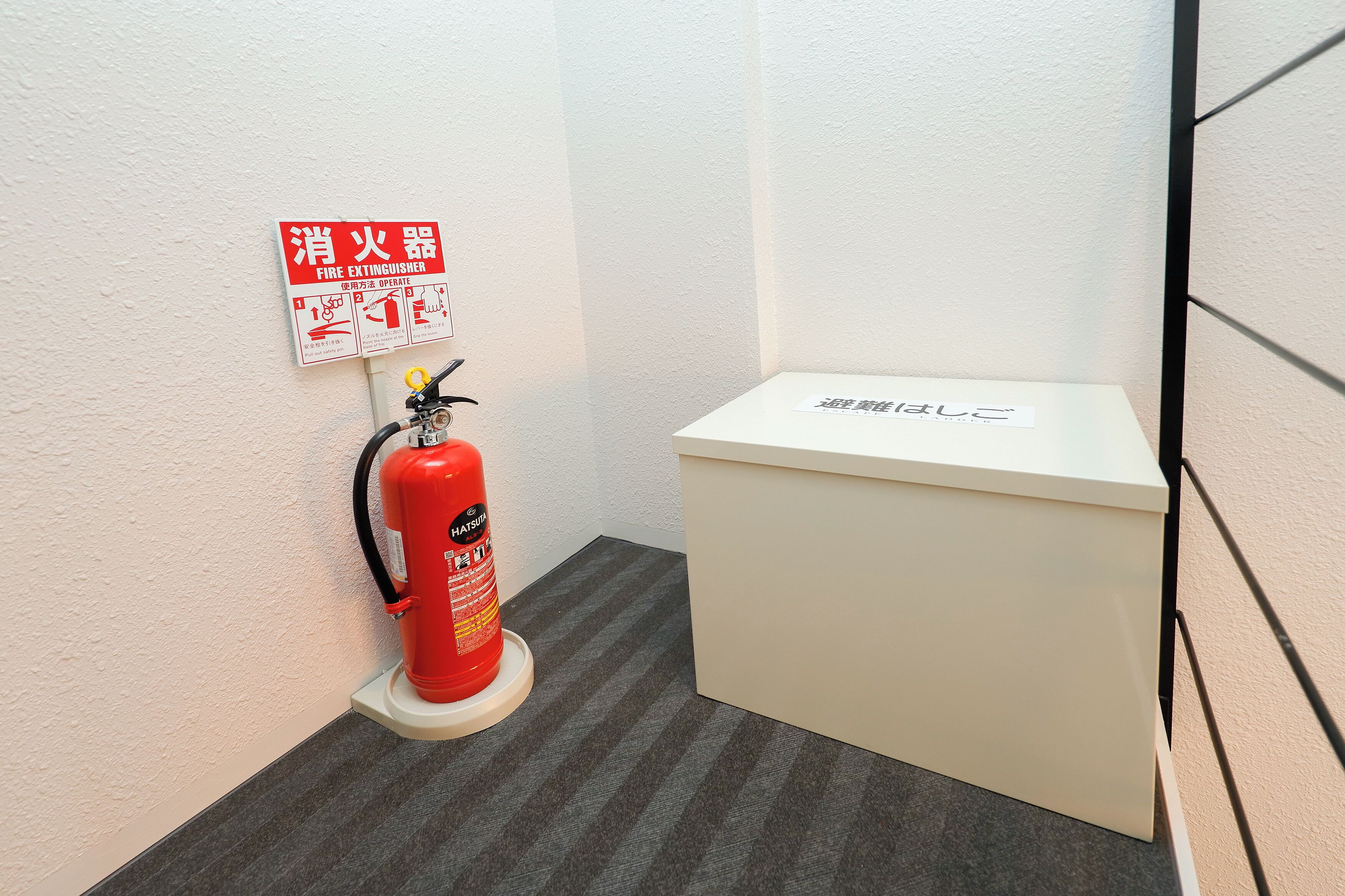 A fire extinguisher mounted on a wall with a white cabinet beside it.