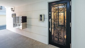 Ingresso moderno di un hotel con una porta nera decorativa, una tastiera di sicurezza e una serie di contenitori per tessere.