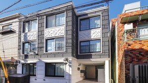 Un edificio residenziale moderno a più piani con tetto piatto, ampie finestre e un ingresso principale con gradini.