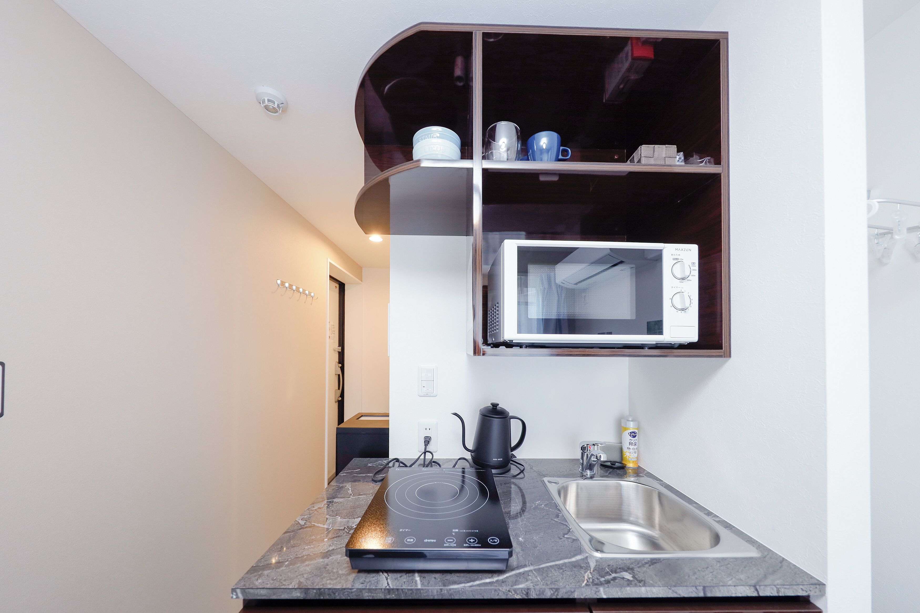 A compact kitchen with a built-in microwave, a kettle, and a sink.