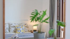 A bedroom with a bed, pillows, a bedside table with a lamp, and a potted plant. - SUITE YAGABO - ARRECIFE - LANZAROTE (Arrecife)