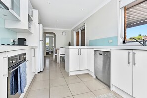 A modern kitchen with white cabinetry, a Bosch dishwasher, and a view of the outdoors through a window.