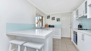 A modern kitchen with a central island, white cabinetry, and a large window providing natural light.