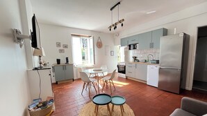 A modern kitchen with a dining area, featuring a refrigerator, stove, microwave, and a dining table with chairs. - Le Palmier - Cosy gîte with all comforts (Chailles)