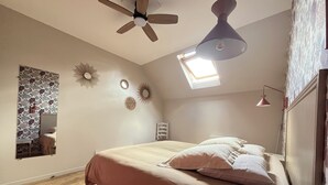 A bedroom with a bed, a ceiling fan, a skylight, and decorative wall mirrors. - Le Palmier - Cosy gîte with all comforts (Chailles)