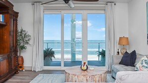 A spacious living room with a large sliding glass door leading to a balcony with a view of the beach. - Just Beachy (Port St. Joe)