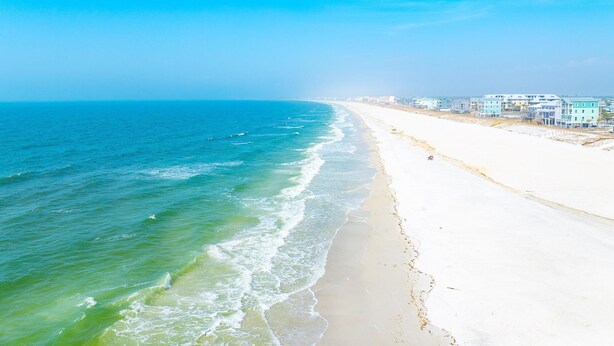 A beach with a clear view of the ocean and a row of buildings along the shore. - Just Beachy (Port St. Joe)