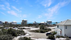 A coastal residential area with houses, a beach, and a clear sky.