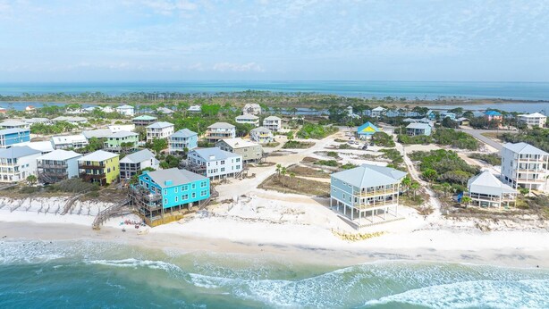 A coastal residential area with beachfront properties, including houses with balconies and a beach house with a pool.