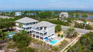 A two-story house with a large balcony, a swimming pool, and a view of the ocean.