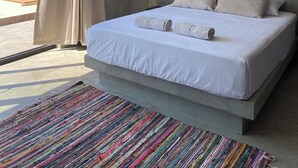 Un dormitorio moderno con una cama grande, un ventilador de techo, un equipo de aire acondicionado y vista al océano.