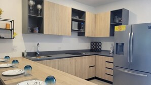 A modern kitchen with wooden cabinets, a stainless steel refrigerator, and a built-in microwave.