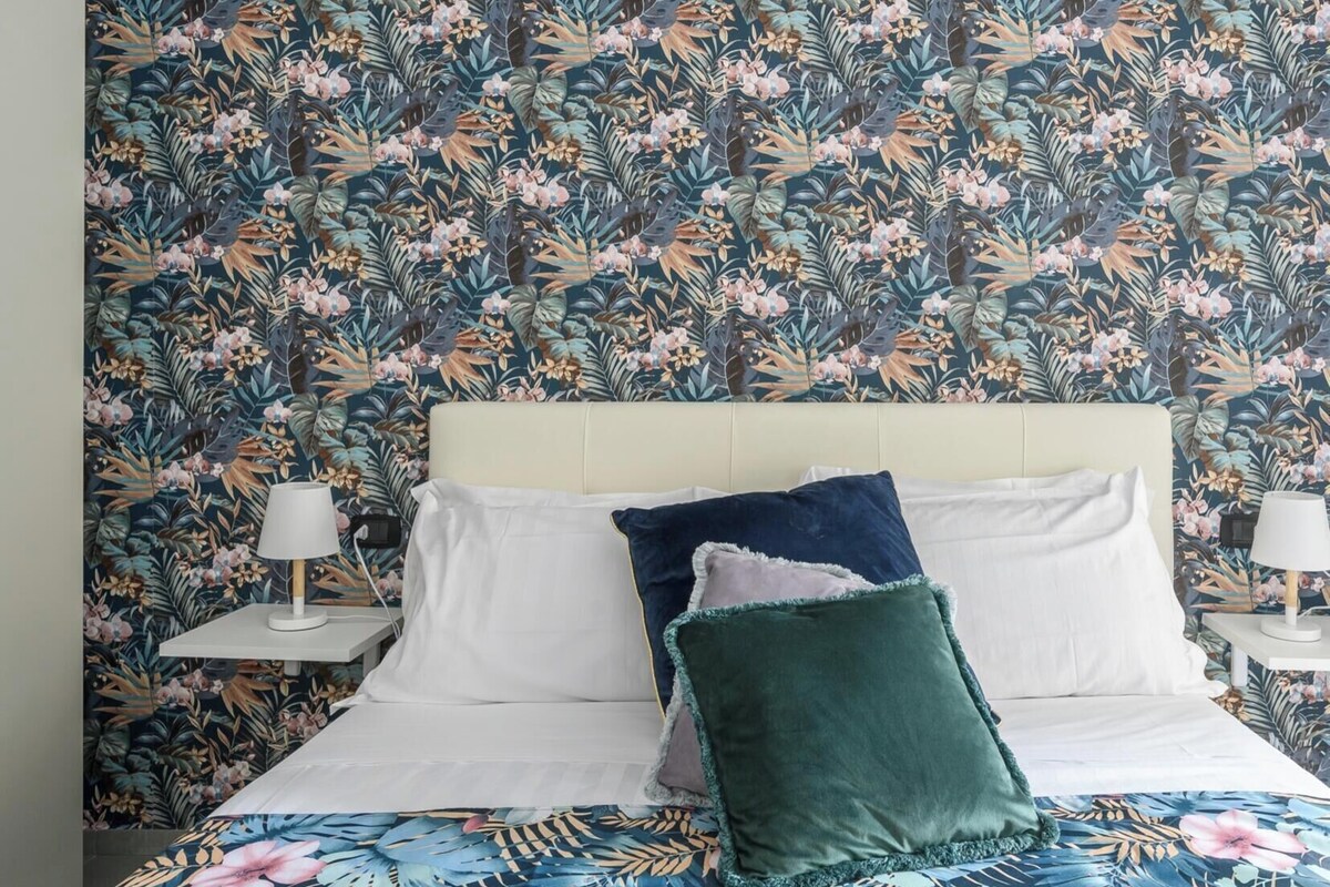 A bed with white linens, two pillows, and a floral-patterned bedspread.