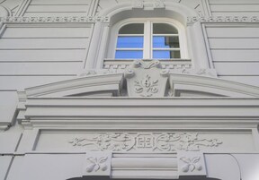 Facciata di un edificio con una finestra, modanature decorative e un design simmetrico.