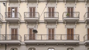 A multi-story building with balconies, decorative moldings, and a bell. - HOTIDAY Room Collection - Napoli Duomo (Naples)