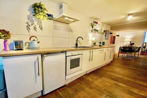 A modern kitchen with white cabinets, a built-in oven, a sink, and a wooden countertop.
