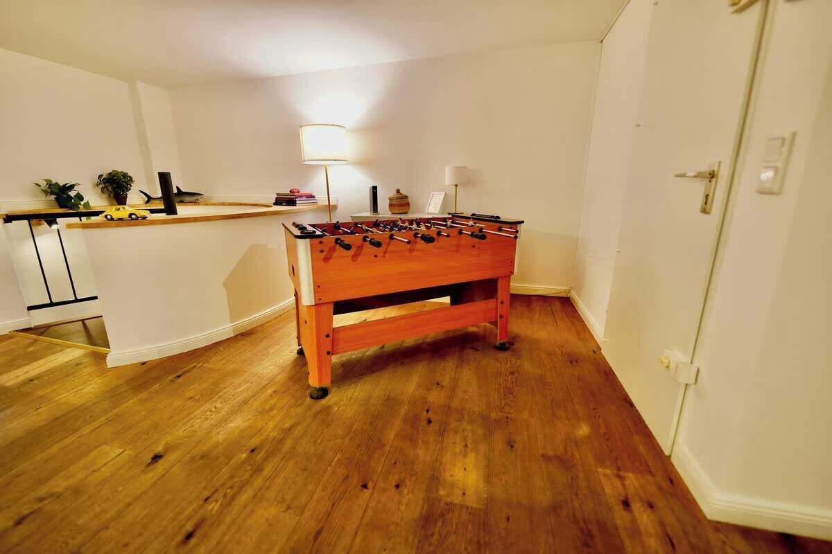 Ein Zimmer mit Holzboden, einem Kicker, einer kleinen Ablage mit Dekoration und einer Tür.