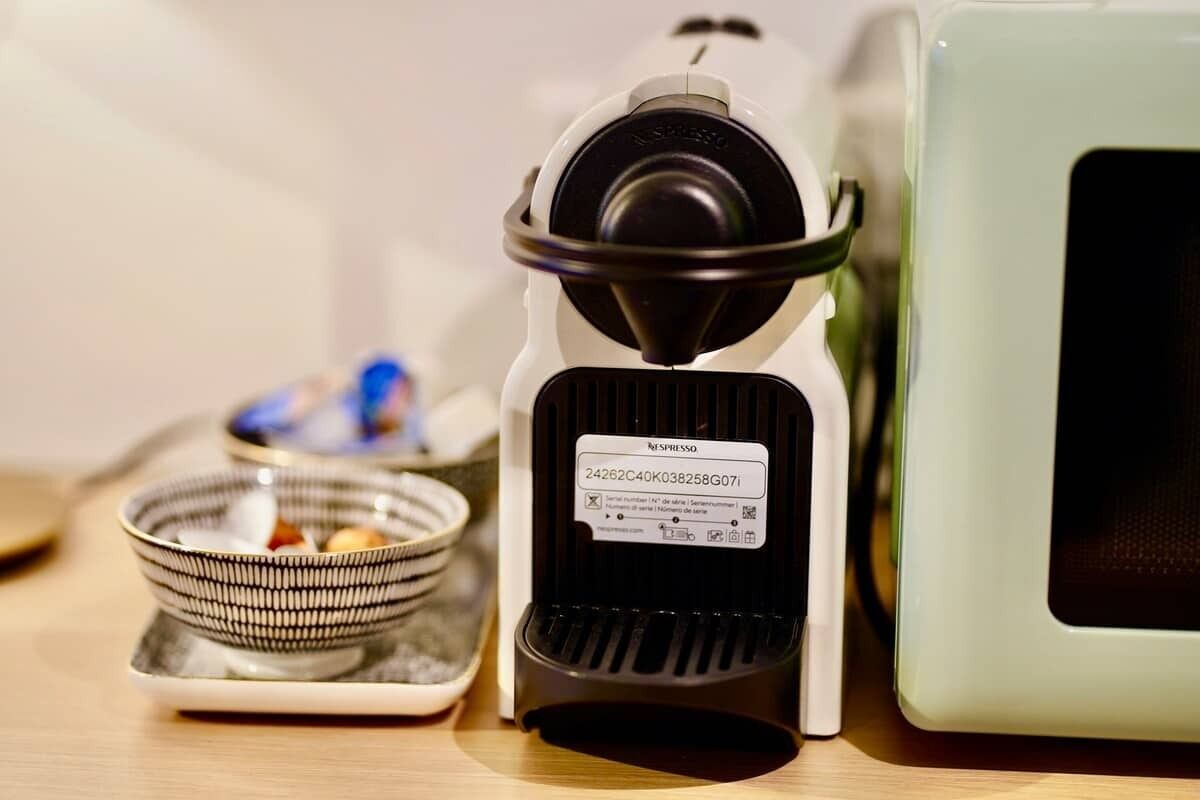 Eine Kaffeemaschine mit Beschriftung, eine kleine Schale mit Deckel und ein grünes Gerät.