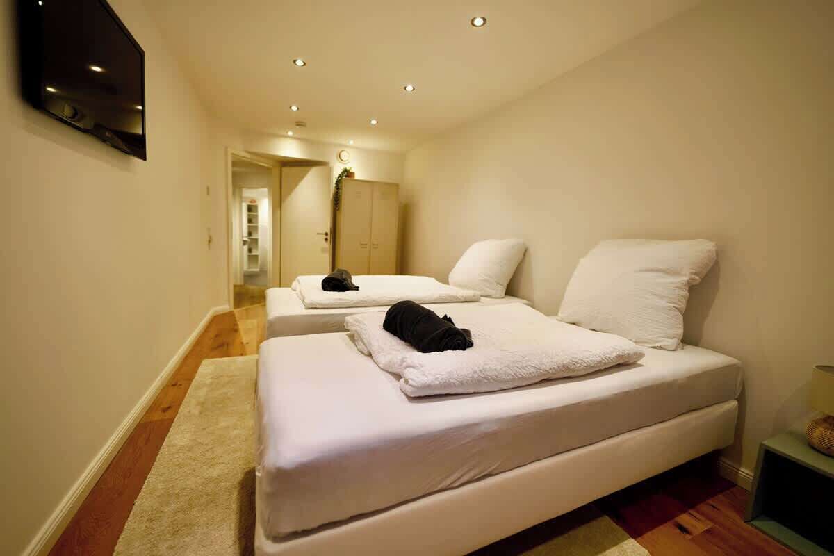 Ein Hotelzimmer mit zwei Betten, einem Flachbildfernseher und Holzboden.