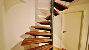 Una escalera de caracol con escalones de madera y un pilar central negro.