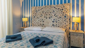 A neatly made bed with blue and white bedding, two bedside lamps, and a decorative headboard. - Il Sogno, apartment with sea view in the historic center of Gaeta (Gaeta)