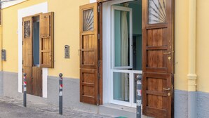 A building with two wooden doors, one open and one closed, and a window with curtains. - Il Sogno, apartment with sea view in the historic center of Gaeta (Gaeta)