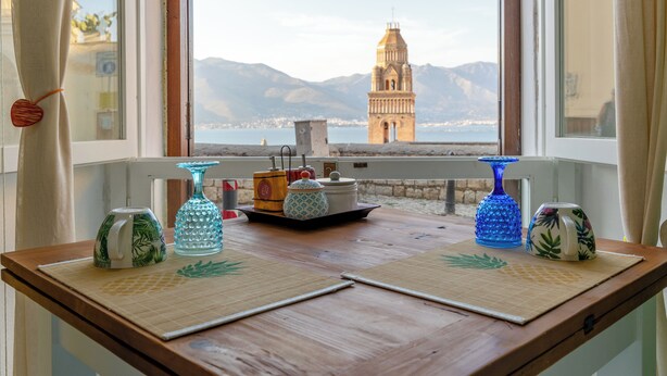 A wooden table with a view of a bell tower and mountains through a window. - Il Sogno, apartment with sea view in the historic center of Gaeta (Gaeta)