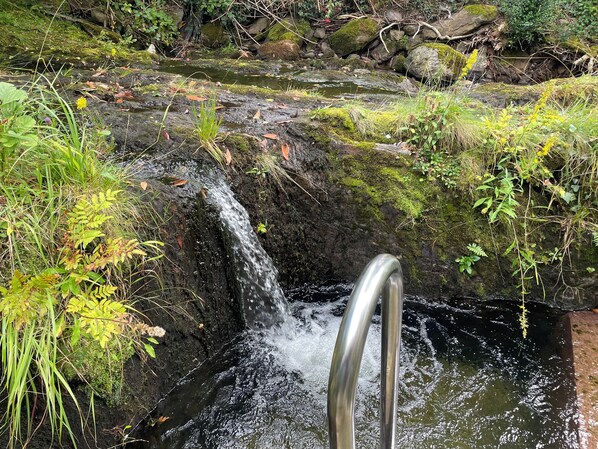 A metal staircase leading down to a small waterfall surrounded by greenery and rocks. - The Jewel Lodge and Spa (Glengarriff)