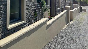 A modern building with stone facade, multiple windows, and a gravel driveway. - The Jewel Lodge and Spa (Glengarriff)