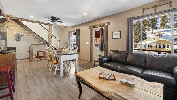 A spacious living room with a dining area, a leather couch, and a staircase leading to an upper level.