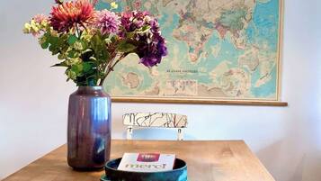 Ein Holztisch mit einem Blumenstrauß, einem Buch und einer Weltkarte an der Wand.