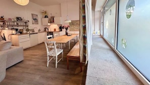 Una cocina moderna con armarios blancos, una mesa de comedor de madera y una lámpara colgante.