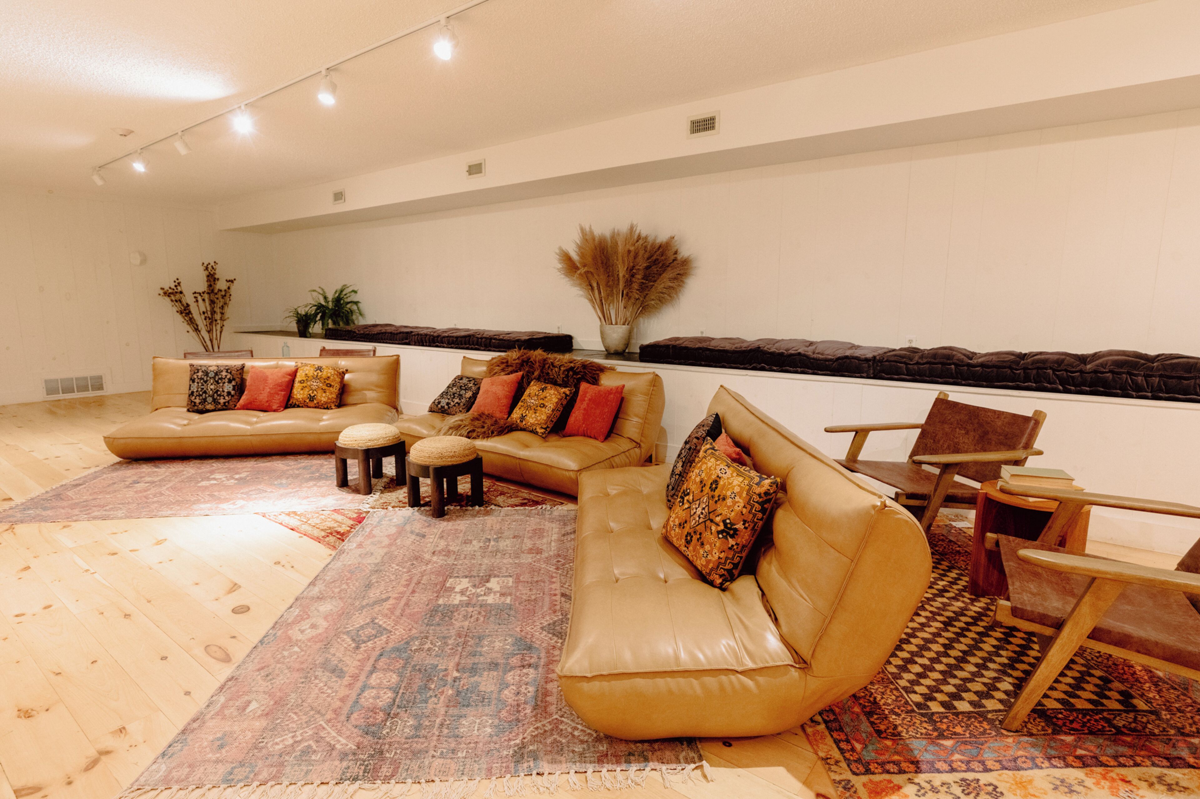 A spacious living room with a large beige sofa set, a patterned rug, and a wooden coffee table.