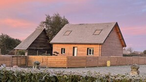 A wooden cabin with a sloped roof and two skylights, surrounded by a wooden fence and a garden with frost-covered plants. - Beautiful wooden house with 3-star rating (Beuzeville)