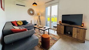 A modern living room with a grey sofa, a television, and a wooden cabinet. - Beautiful wooden house with 3-star rating (Beuzeville)