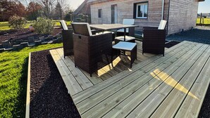 A wooden deck with outdoor furniture, a house with a sloped roof, and a clear sky. - Beautiful wooden house with 3-star rating (Beuzeville)