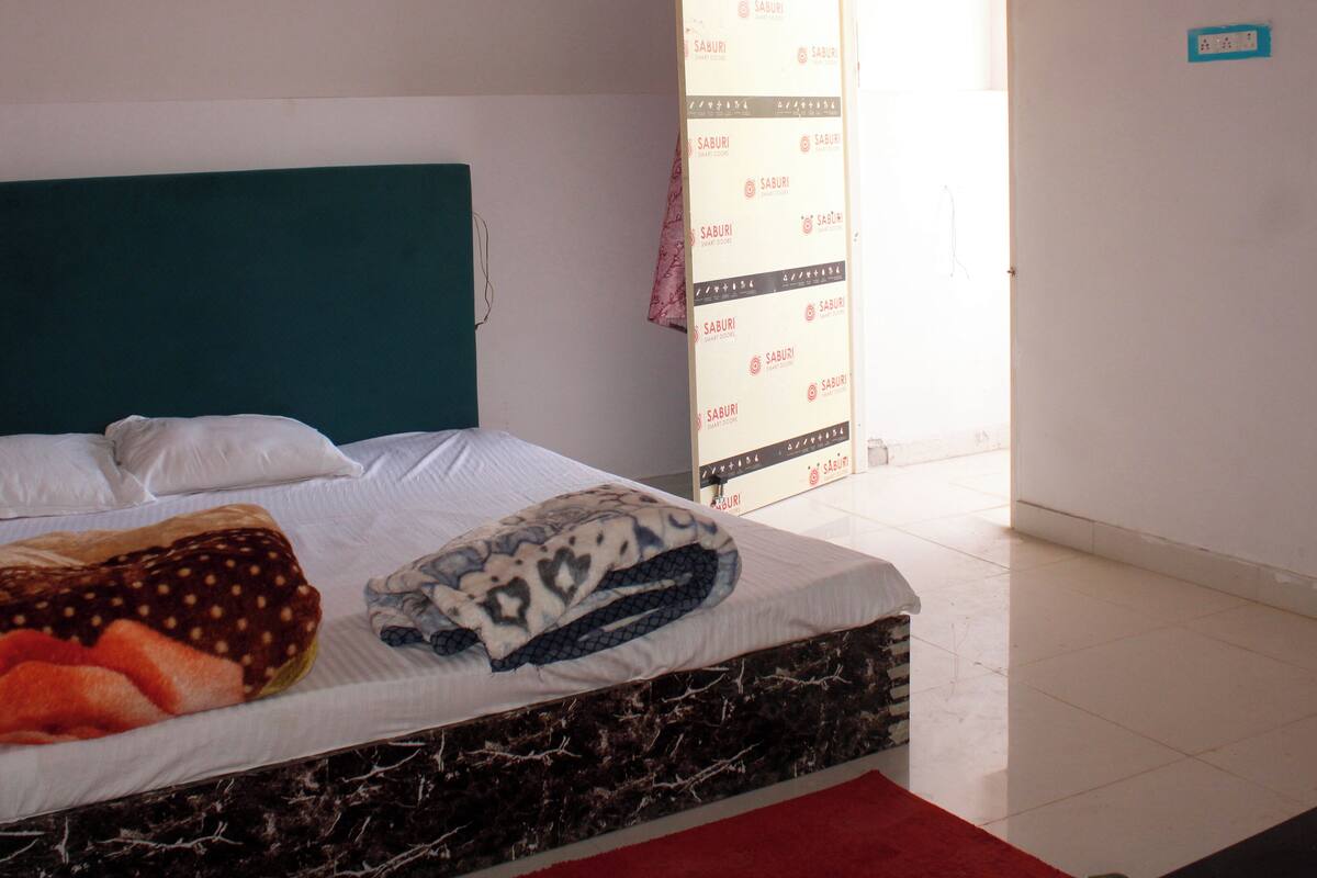 A bed with a teal headboard, white bedding, and a patterned blanket.
