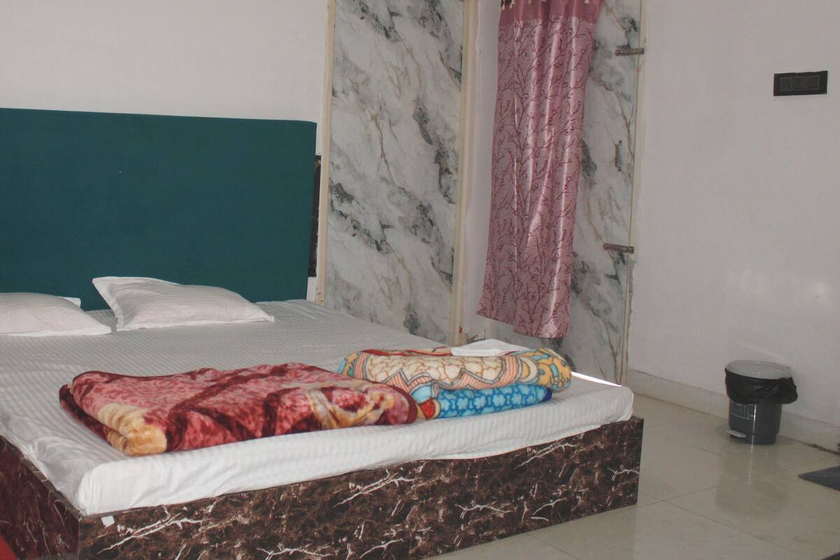 A bed with a green headboard, white pillows, and a patterned blanket.