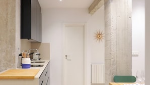 Una cocina moderna con encimera de madera, un fregadero y una estufa. Se observa una puerta blanca y un adorno de pared con forma de estrella.