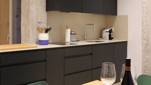 Una cocina moderna con armarios oscuros, encimera de madera, un lavabo y una zona de comedor con mesa y sillas.