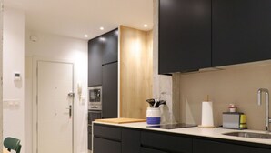Una cocina moderna con armarios oscuros, una encimera de madera y un horno empotrado.