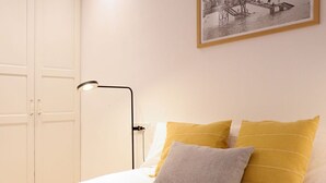 Un dormitorio con cama, armario blanco y lámpara de escritorio.