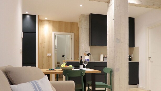 Un espacio habitable compacto con comedor, kitchenette y sofá.