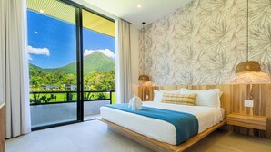 Ein modernes Schlafzimmer mit einem großen Bett, Blick auf Grünflächen und Berge, sowie einer Wand mit Musterung.
