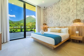 A modern bedroom with a large bed, a view of greenery and mountains, and a patterned wall.