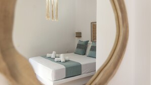 A neatly made bed with a white and teal bedspread, a teal throw blanket, and a white pillow. - Summer Residence (Milos)