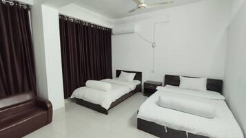 A hotel room with two beds, a ceiling fan, and a window with curtains.