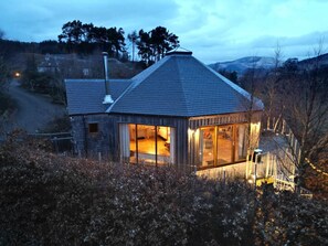 Una casa moderna con un gran ventanal, un techo inclinado y una chimenea.