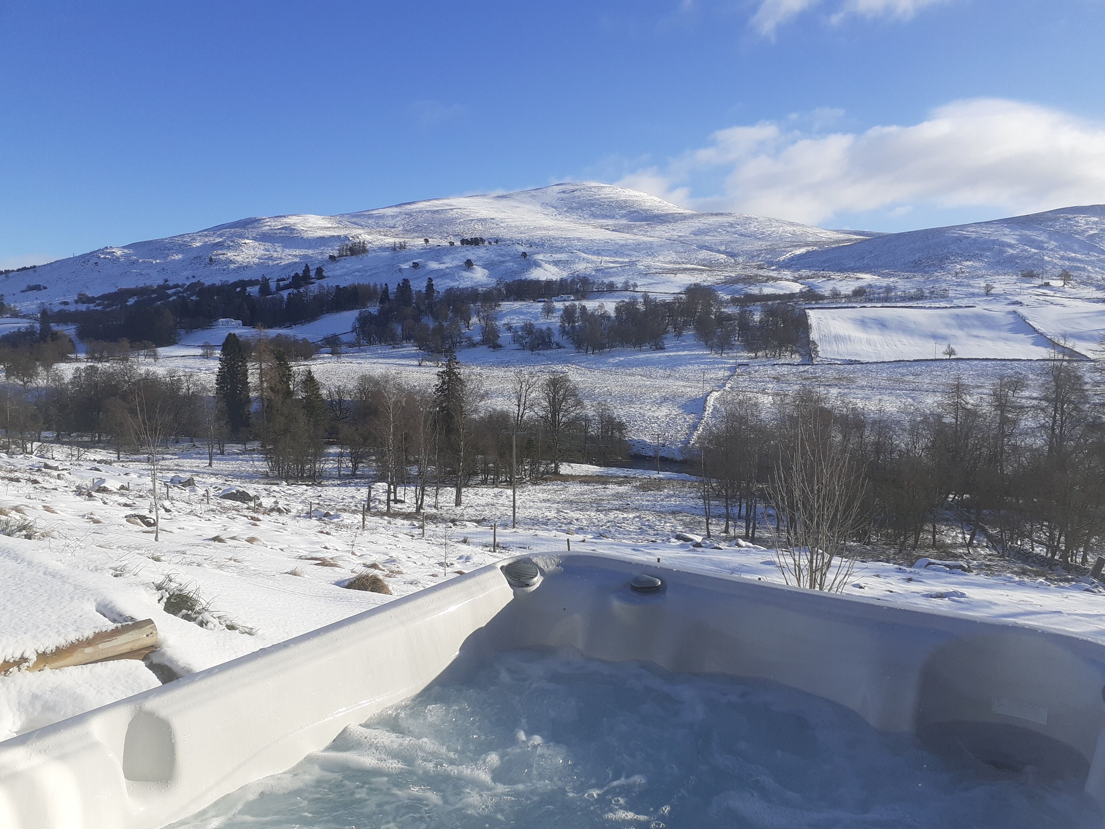 Paisaje nevado con una bañera de hidromasaje al frente.